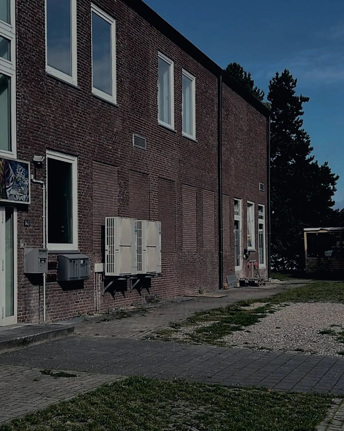 Backsteingebäude mit Hoffläche, Gehweg und Stellplätzen bei Tageslicht
